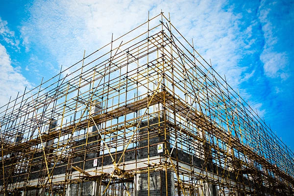 Building under construction with scaffolding against a blue sky.