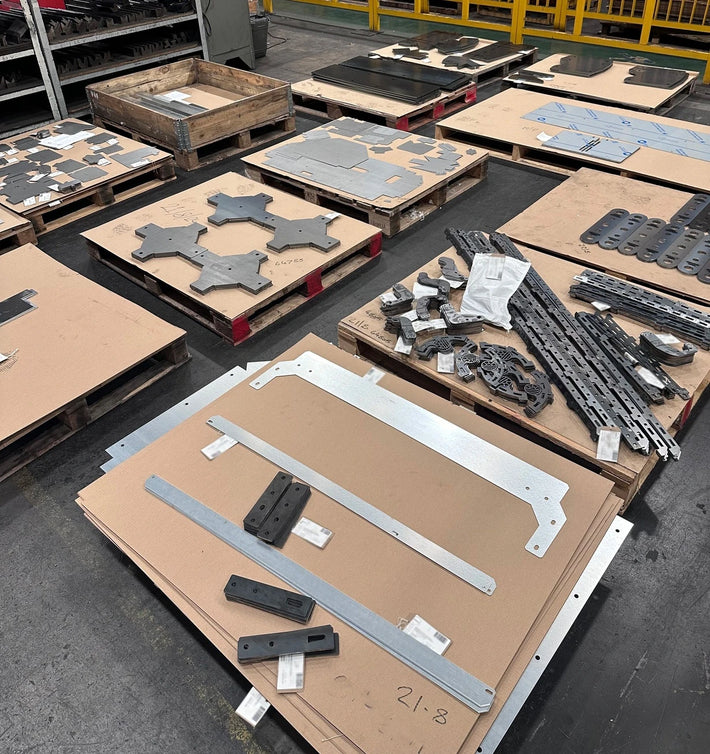 Laser cut parts on top of carboard and pallets ready to be folded on a press brake.