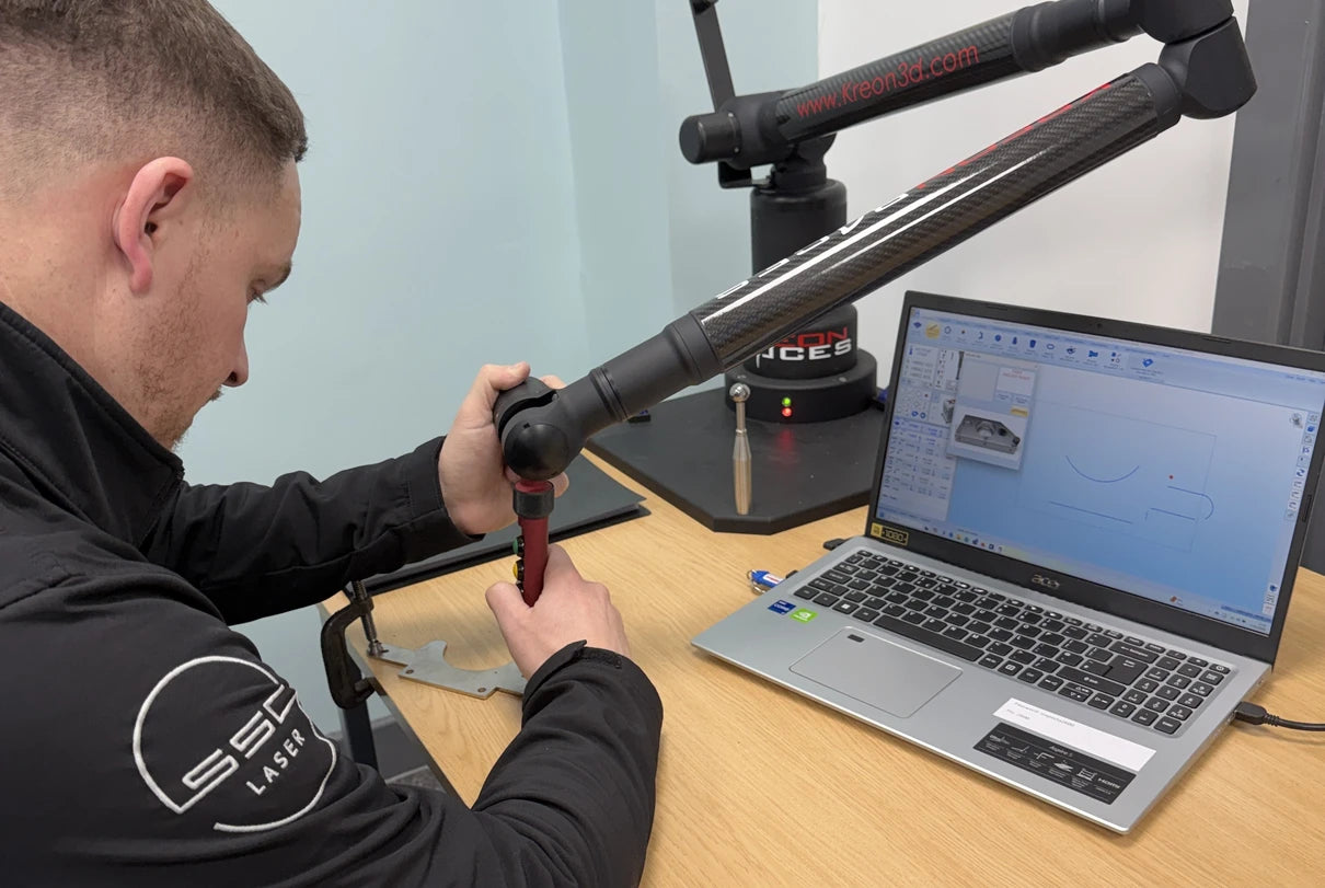 Person working on a mechanical object with a laptop displaying a design software interface.