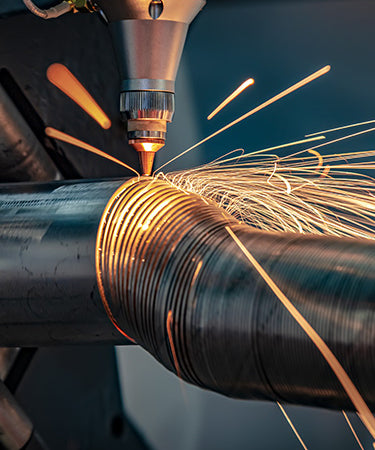 Tube laser cutting a spiral out of a round metal tube with sparks flying