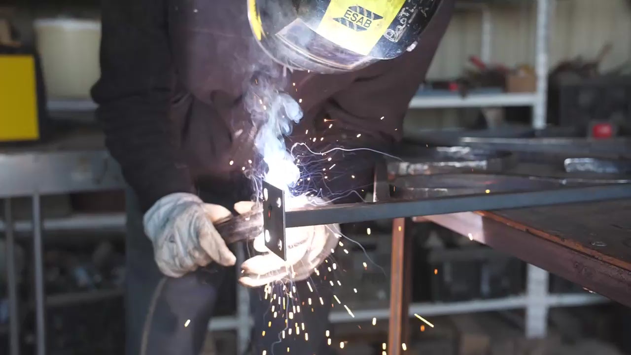 Person operating at a welding bay working on mild steep components while wearing safety equipment